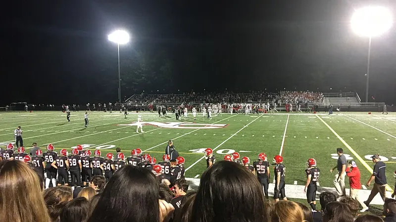 American football game under stadium floodlights