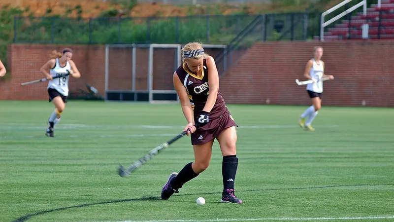 Field hockey player dribbling a ball on an outdoor pitch