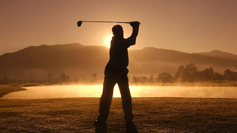 Silhouette of a golfer swinging at sunset