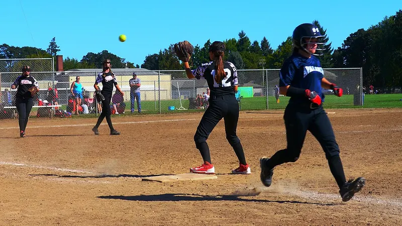 Softball pitcher delivering a ball with fielders behind
