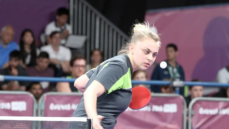 Table tennis player striking a ball with a paddle